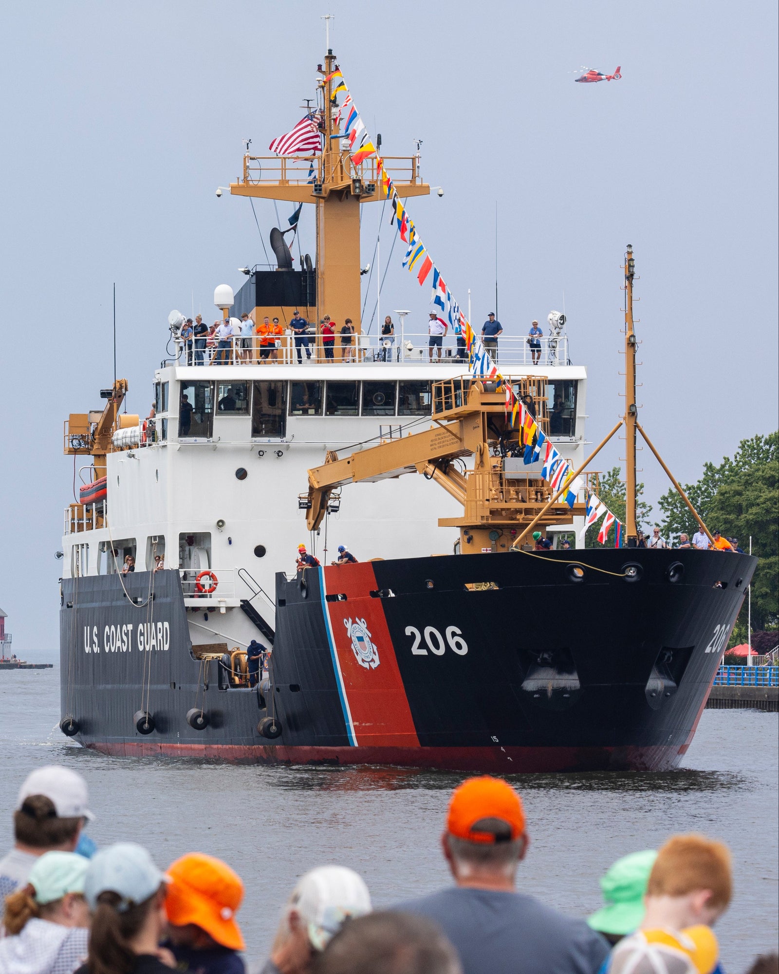 Large U.S. Coast Guard ship with people watching from the shore.